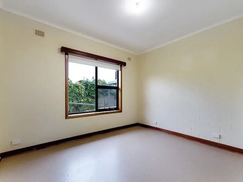 Second bedroom with a large timber-framed window and garden outlook