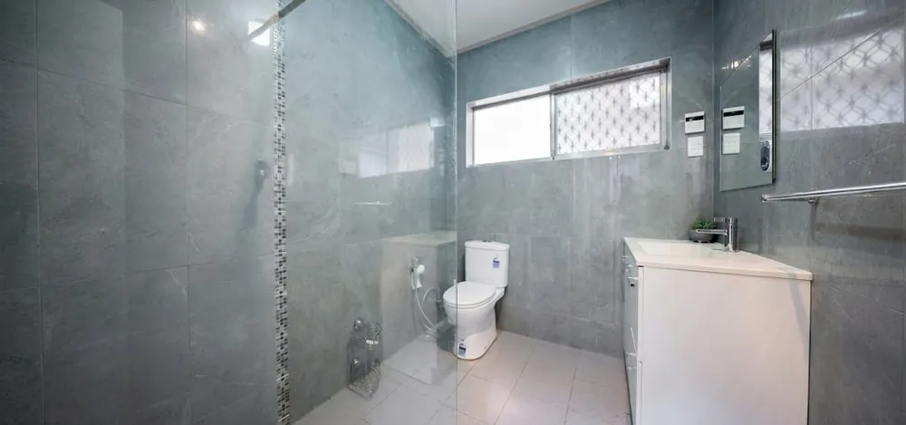 Grey-tiled bathroom with a step-free glass-screen shower, vanity and toilet