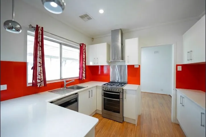 Renovated kitchen with red glass splashback, stainless rangehood, gas stove and dishwasher